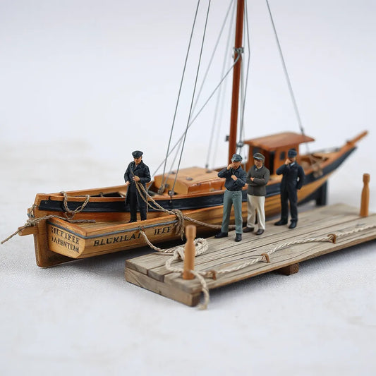 Painted crew figures posed on a dock next to a small model boat diorama