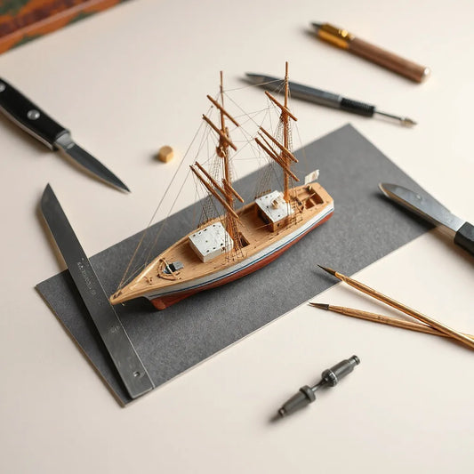 Model ship building tools arranged on a workbench beside a scale hull in progress